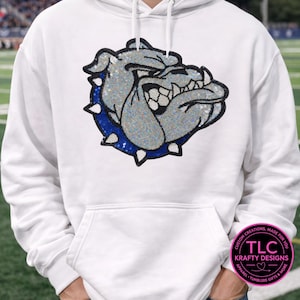 May include: White hoodie featuring a sparkling, gray bulldog head design with a blue collar. The design is embellished with small, reflective elements. The hoodie includes a drawstring hood and a kangaroo pocket. The design is from TLC Krafty Designs.