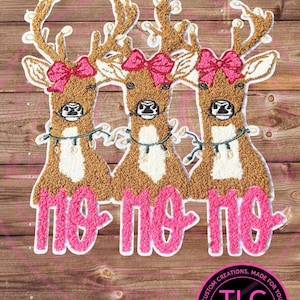 May include: Three brown reindeer with white accents, each wearing a pink bow and a string of lights. The word "no-no-no" is written in pink script below. The image is on a wooden background.