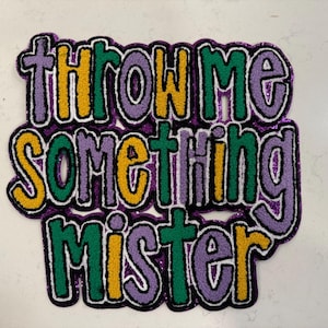 May include: A colorful patch with the phrase "THROW ME SOMETHING MISTER" in large, stylized letters. The text features a purple background with yellow, green, and black accents, perfect for a Mardi Gras theme.