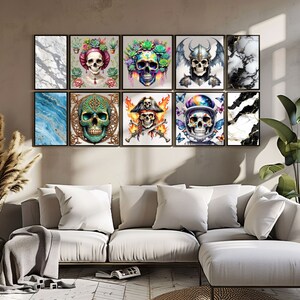 May include: A set of nine framed prints featuring colorful skull illustrations. The prints are arranged in a grid pattern on a wall above a white couch. The skulls are depicted in various styles, including a pirate skull, a viking skull, and a skull with flowers.
