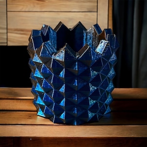 May include: A blue geometric vase with a textured surface. The vase is made of a shiny material and has a unique, modern design.