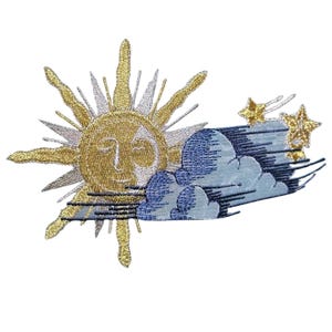Puede incluir: Un parche bordado que presenta un sol dorado con un rostro estilizado, rodeado de rayos alternos en oro y plata. A la derecha, nubes azules y blancas se superponen al sol, acompañadas por dos pequeñas estrellas doradas brillantes.