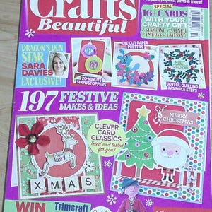 May include: The cover of "Crafts Beautiful" magazine, October 2019 issue, features festive Christmas craft ideas. The cover is predominantly pink and includes images of Christmas cards, a reindeer, Santa Claus, and the text "197 Festive Makes & Ideas."