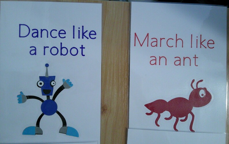 May include: Two educational posters. One says "Dance like a robot" with a blue robot illustration. The other says "March like an ant" with a red ant illustration. Both are on white backgrounds.