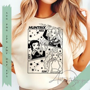 Puede incluir: Camiseta color crema con un gráfico en blanco y negro estilo cómic. El gráfico incluye tres personajes femeninos llamados Mira, Zoey y Rumi, con el texto "Huntrix" arriba. El diseño está rodeado de estrellas.