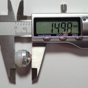 May include: A silver digital caliper measuring a small white and silver object. The caliper reads 1.498 mm.