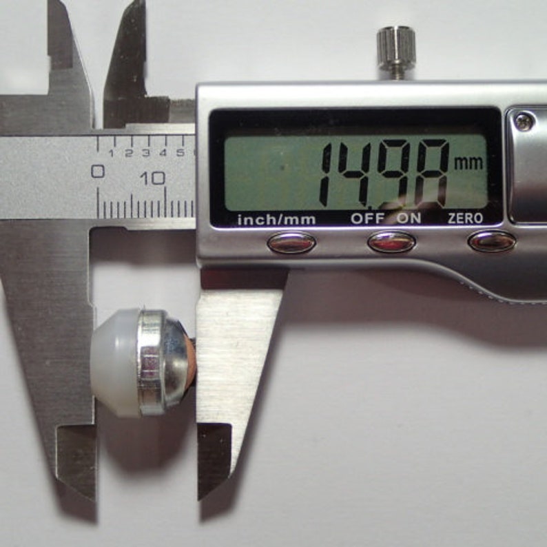 May include: A silver digital caliper measuring a small white and silver object. The caliper reads 1.498 mm.