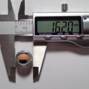 May include: A silver-colored metal object is being measured with a digital caliper. The caliper reads 16.20 mm.