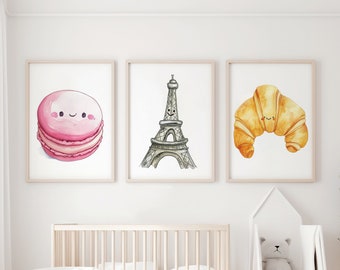 Può includere: Tre illustrazioni ad acquerello in cornici bianche su una parete bianca. Le illustrazioni sono di un macaron rosa, la Torre Eiffel e un croissant. Tutte e tre le illustrazioni hanno facce sorridenti.
