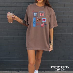 May include: Brown Comfort Colors espresso t-shirt with a graphic design featuring the text "GO BUFFALO" and various Buffalo-themed images. The shirt has a relaxed fit and short sleeves. The text "COMFORT COLORS espresso" is printed at the bottom.