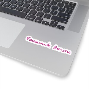 May include: A white sticker with the text "Faaawwk Aaron" in a cursive, magenta font. The sticker is placed on a silver laptop, with the keyboard visible in the background.