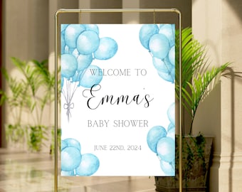 Puede incluir: Un marco dorado sostiene un letrero blanco con globos azules de acuarela. El letrero dice "Welcome to Emma's Baby Shower" y "June 22nd, 2024". El letrero es un elemento decorativo para un baby shower.