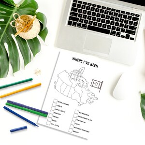 May include: A white sheet of paper with the text "WHERE I'VE BEEN" and a map of Canada, with check boxes for each province and territory. A laptop, pens, and a monstera leaf are also visible.