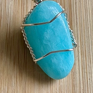 May include: A light blue aquamarine gemstone wrapped in silver wire, creating a pendant.