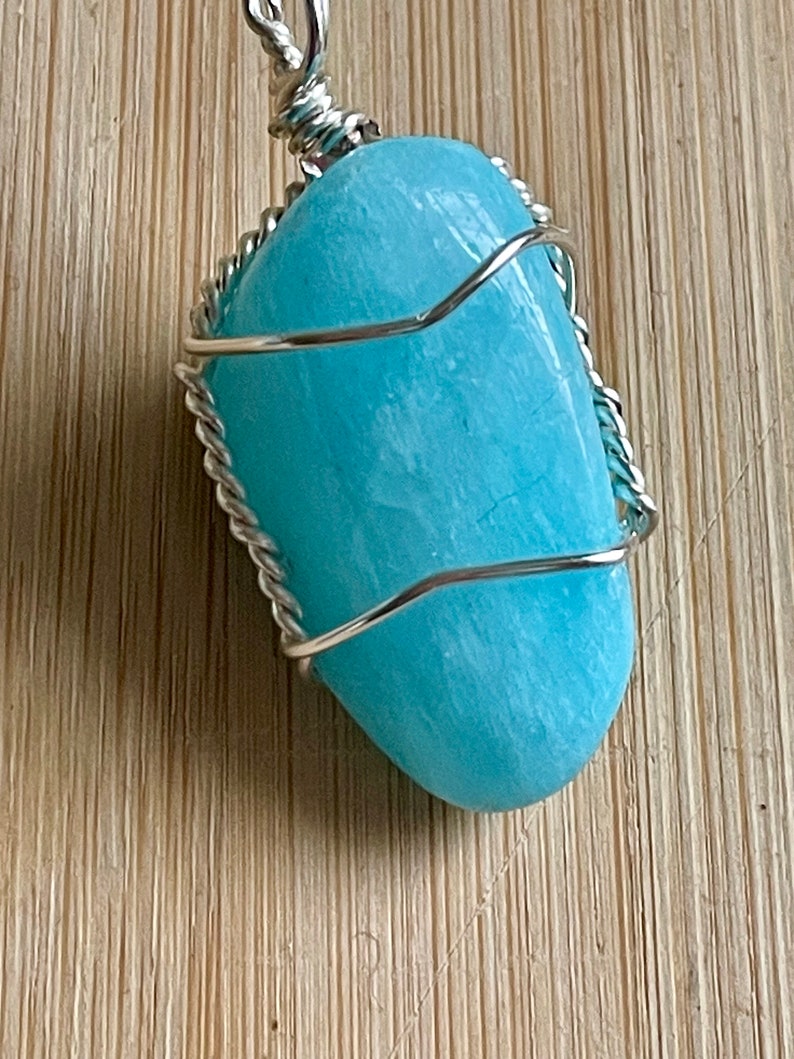 May include: A light blue aquamarine gemstone wrapped in silver wire, creating a pendant.
