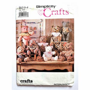 May include: A Simplicity Crafts pattern envelope, number 9894, featuring illustrations of seven handmade teddy bears in various floral and patterned fabrics. The bears wear decorative collars and vests, displayed on a wooden table and shelf.