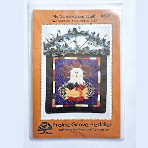 May include: A sewing pattern packet titled My Scarecrow Quilt #321 by Prairie Grove Peddler. The cover features a quilt design with a scarecrow holding a red heart, available in 142 cm by 157 cm and 76 cm by 84 cm sizes.