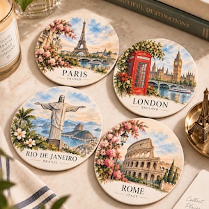 Peut inclure: Quatre dessous de verre ronds en céramique illustrés de monuments mondiaux. L'un représente la tour Eiffel à Paris, un autre la cabine téléphonique rouge et Big Ben à Londres, le troisième le Christ Rédempteur à Rio de Janeiro et le quatrième le Colisée à Rome.