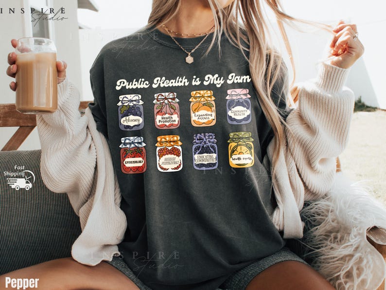K&ouml;nnte beinhalten: Dunkelgraues T-Shirt mit dem Text "Public Health is My Jam" und Illustrationen von Marmeladengl&auml;sern. Jedes Glas hat ein anderes Etikett, darunter "Advocacy" und "Health Promotion".