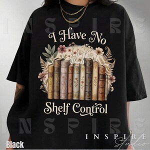 May include: Black t-shirt with the text "I Have No Shelf Control" above a graphic of a row of books surrounded by flowers and foliage. The design features a vintage aesthetic with muted colors.