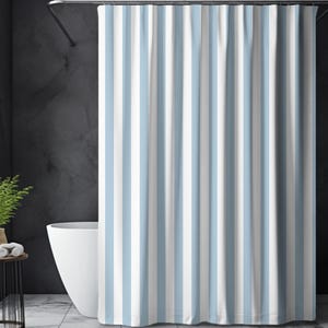 May include: A shower curtain with vertical stripes in light blue and white. The curtain hangs in front of a white bathtub, with a dark gray wall in the background. The curtain is made of a soft, opaque material.