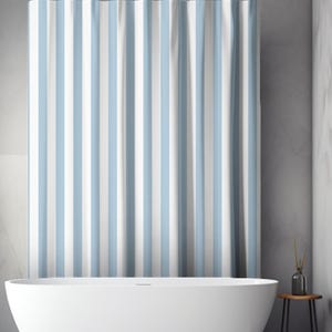 May include: A shower curtain with vertical stripes in light blue and white. The curtain hangs from a black rod above a white bathtub. The bathroom has a minimalist design with a neutral color palette.