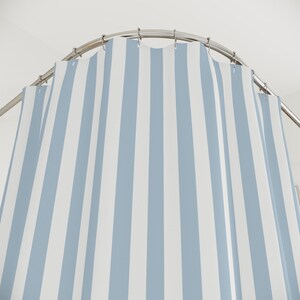 A light blue and white striped shower curtain; minimalist, modern, beachy aesthetic.