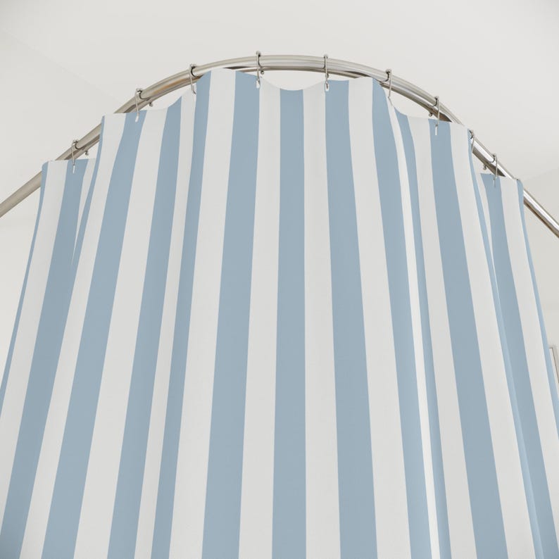A light blue and white striped shower curtain; minimalist, modern, beachy aesthetic.