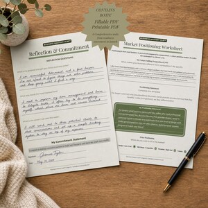 May include: Two white business worksheets titled Reflection & Commitment and Market Positioning Worksheet with black text and green accents. The pages contain printed questions and handwritten responses in blue ink, accompanied by a black ballpoint pen.