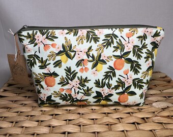 May include: A white zippered pouch with a green zipper and a floral print featuring lemons, oranges, and pink flowers.