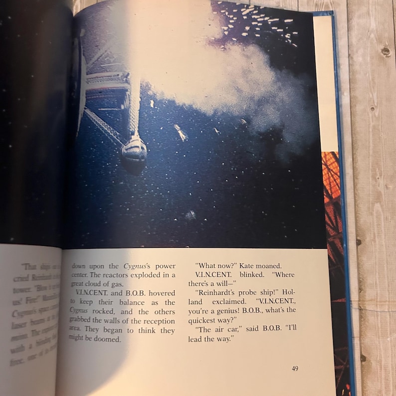Op de afbeelding: Een open boekpagina met een dramatische illustratie van een ruimteschip en een gaswolk. Tekst op de pagina beschrijft een sciencefiction-sc&egrave;ne met de personages V.I.N.CENT en B.O.B. Het paginanummer 49 is zichtbaar.