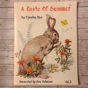 May include: A vintage book cover titled "A Taste of Summer" with a brown rabbit illustration and orange and yellow flowers. The cover also includes the text "By Claudia Nice" and "Presented by Sue Scheewe".