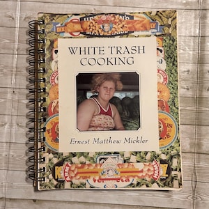Może przedstawiać: Spiralnie oprawiona książka kucharska zatytułowana "WHITE TRASH COOKING" autorstwa Ernesta Matthew Micklera. Okładka zawiera zdjęcie kobiety i jest otoczona przez stare etykiety żywności. Spiralna oprawa.