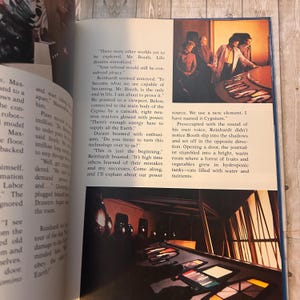 Op de afbeelding: Een open boek met illustraties en tekst. E&eacute;n illustratie toont een groep mensen in een kamer met een bedieningspaneel. De tekst gaat over exploratie en technologie.