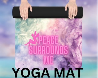 May include: A rolled up yoga mat with a watercolor-style design in shades of purple, pink, and green. The text "PEACE SURROUNDS ME" is printed in pink on the mat.
