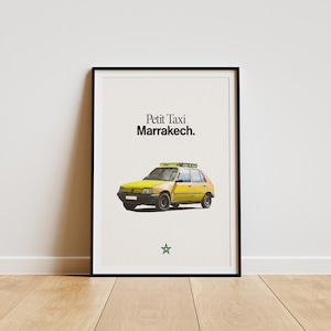May include: A framed print featuring a yellow taxi with the text "Petit Taxi Marrakech." The taxi has a green light on top and is set against a cream-colored background. A green star is at the bottom.