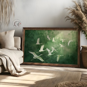 May include: A framed print of a green watercolour background with white silhouettes of cranes flying in formation. The print is in a wooden frame.