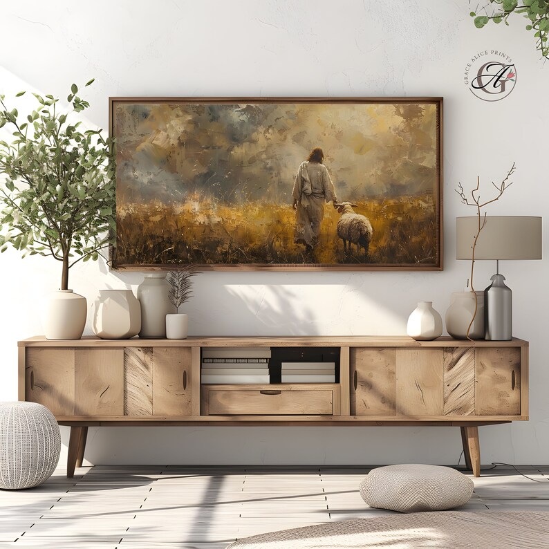 May include: A painting of a man in a white robe walking with a sheep in a field. The sky is cloudy and the sun is shining through the clouds. The painting is framed in a wooden frame.