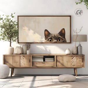 以下が含まれることがあります： 壁の後ろから顔を出している猫の絵。猫は茶色と灰色の毛並みで、大きく明るい黄色の目をしています。背景は薄いベージュ色です。