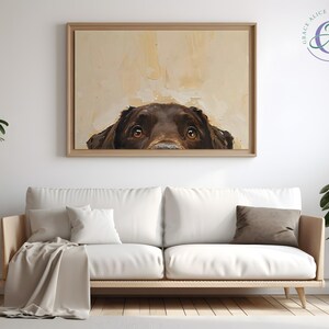 Puede incluir: Una pintura de un perro marr&oacute;n asom&aacute;ndose por la parte superior de un lienzo. Los ojos del perro miran directamente al espectador. La pintura est&aacute; enmarcada en un marco de madera claro y est&aacute; colgada en una pared blanca.