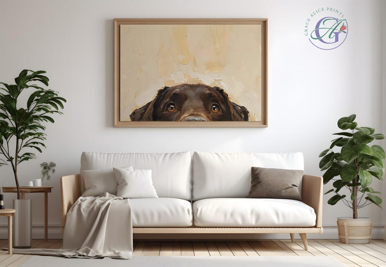 Puede incluir: Una pintura de un perro marr&oacute;n asom&aacute;ndose por la parte superior de un lienzo. Los ojos del perro miran directamente al espectador. La pintura est&aacute; enmarcada en un marco de madera claro y est&aacute; colgada en una pared blanca.
