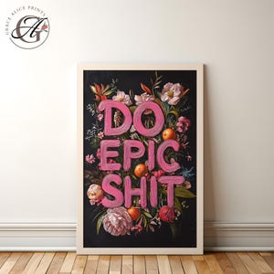 Op de afbeelding: Een ingelijste kunstprint met een zwarte achtergrond en roze letters die "DO EPIC SHIT" lezen. De letters worden omringd door een bloemstuk van roze, witte en rode bloemen, groene bladeren en oranje citrusvruchten.