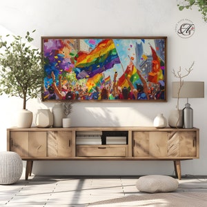 Pode incluir: Uma pintura colorida de uma multidão de pessoas celebrando com bandeiras arco-íris e confete. A pintura é emoldurada e pendurada em uma parede acima de um armário de madeira.