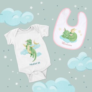 May include: A white baby bodysuit with a green dragon illustration and the name "Mason" printed on the front. A pink bib with a sleeping green dragon illustration and the name "Medison" printed on the front.
