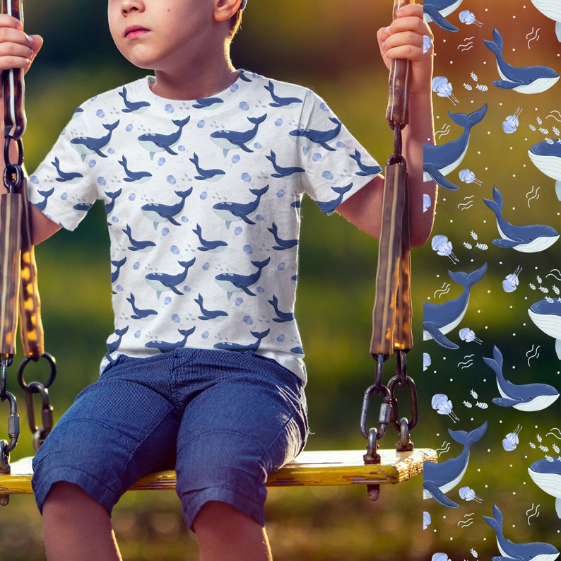K&ouml;nnte beinhalten: Ein Kind tr&auml;gt ein wei&szlig;es T-Shirt mit einem blauen Walmuster. Das Shirt hat einen Rundhalsausschnitt und kurze &Auml;rmel. Das Kind sitzt auf einer gelben Schaukel.