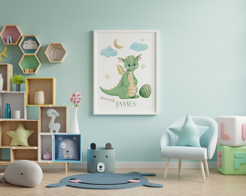 May include: A light blue armchair with a star-shaped pillow sits in a nursery with a green dragon watercolor print on the wall. The print has the name "JAMES" at the bottom.