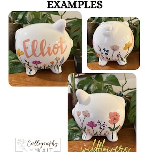 May include: White ceramic piggy banks with custom designs. One bank has the name "Elliot" in pink script, and another says "wildflowers" in yellow script. Each bank is decorated with colorful floral designs.