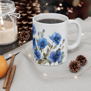 May include: White ceramic mug with a blue floral design. The mug is filled with coffee and steam is rising from the top.