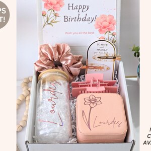 May include: A gift box with a birthday card, scrunchie, hair clips, and a personalized jar and jewelry case. The card reads "Happy Birthday!" and "Wish you all the best." The jar and case are personalized with the name "Lourdes."