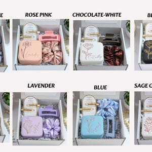May include: Gift boxes with hair accessories in various colors. Each box contains a hair clip, scrunchie, and a small box with a floral design and a name. Colors include dusty blue, rose pink, chocolate, black, white, lavender, blue, and sage green.